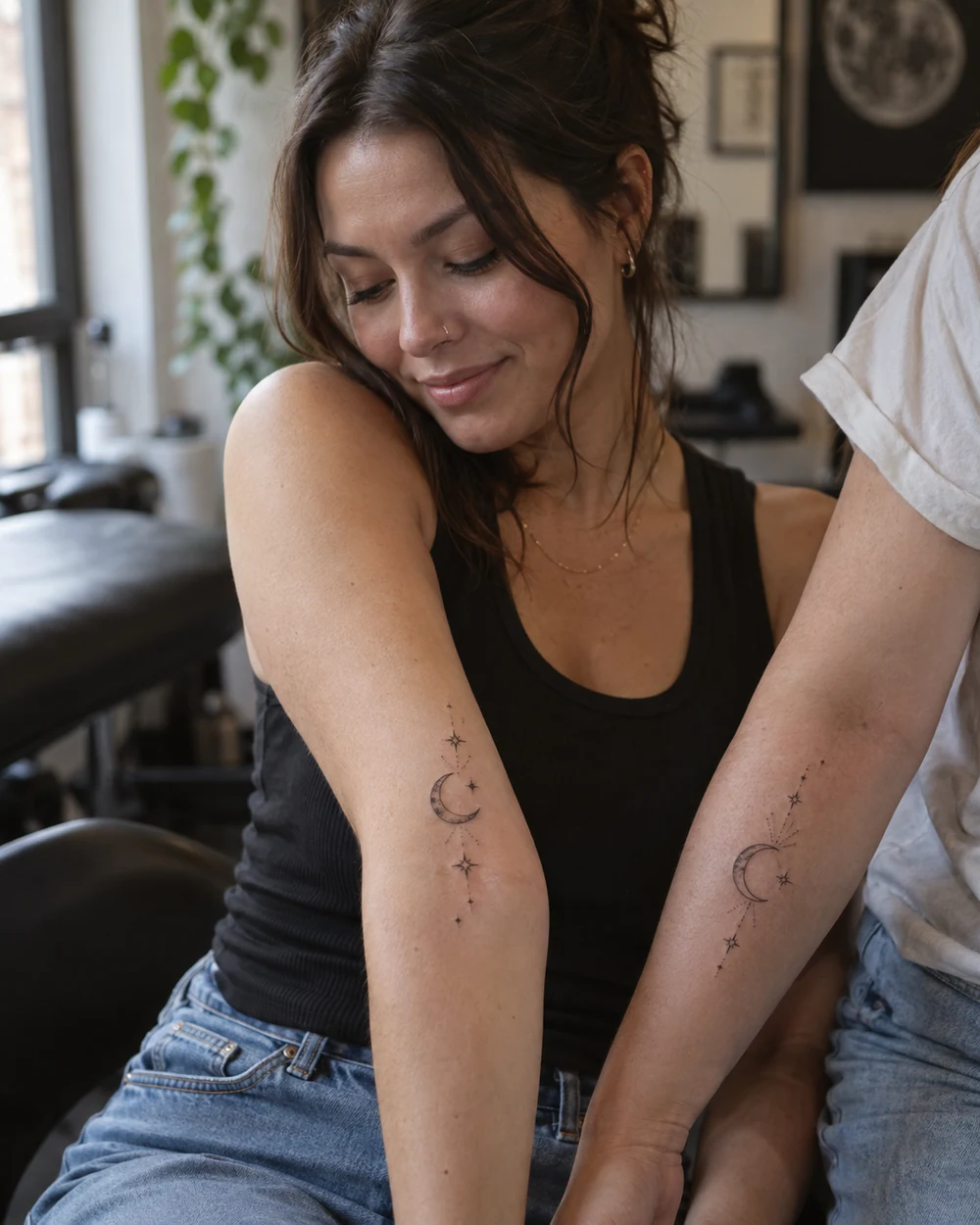Two crescent moon and tiny star tattoos on a woman's outer forearm and a second person's forearm