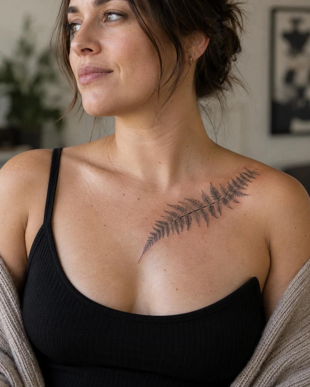 Fine-line fern frond tattoo angled across the upper chest toward a collarbone