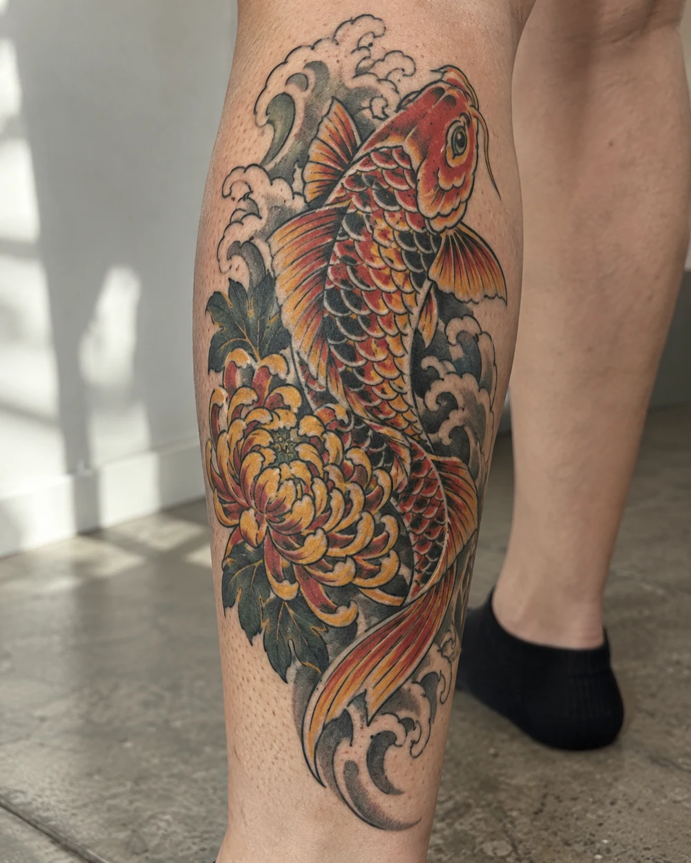 Traditional koi fish tattoo passing a chrysanthemum on a calf