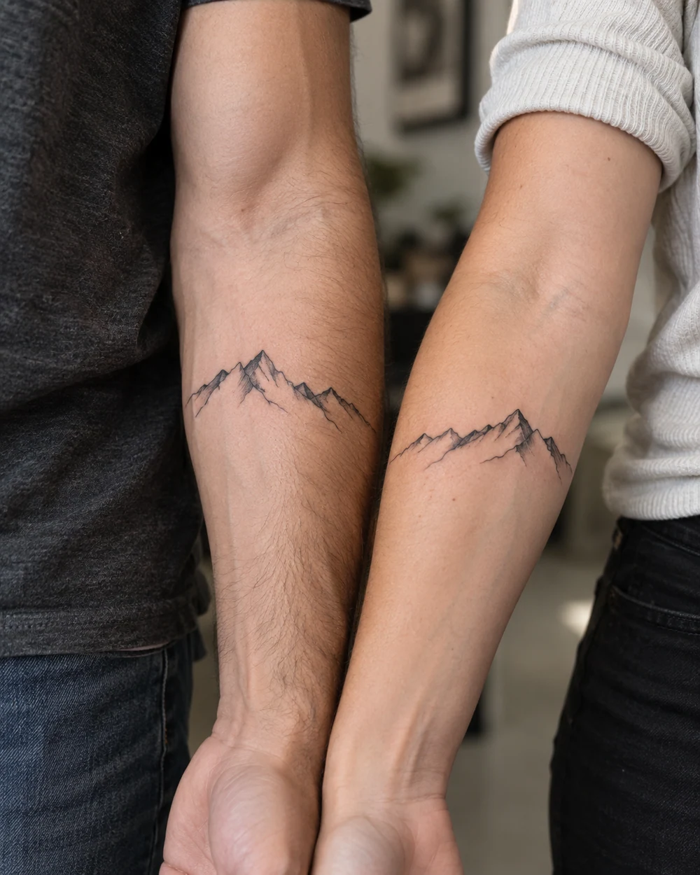 Complementary fine-line mountain tattoos on two adult forearms