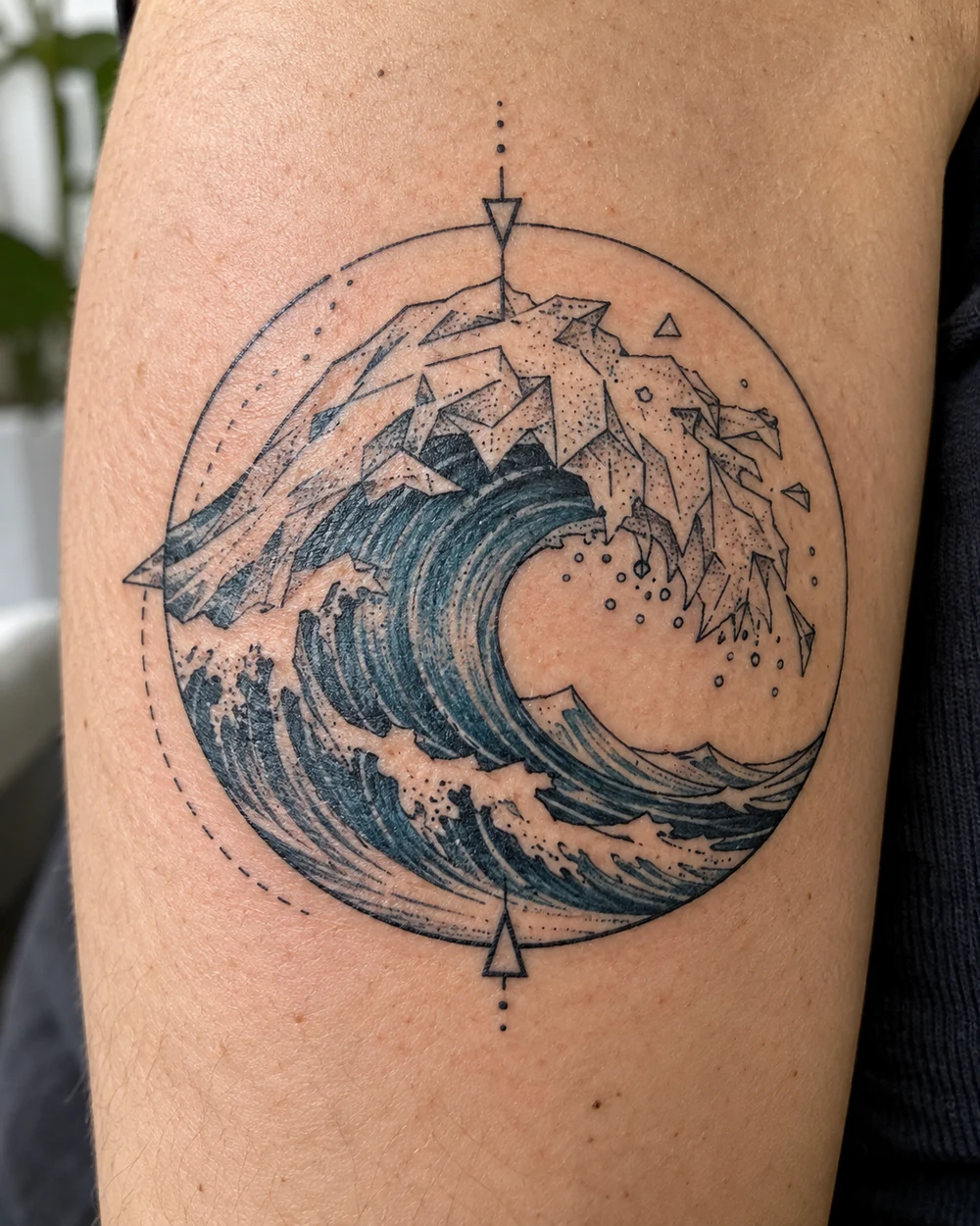 Geometric ocean wave tattoo curling inside a circle, with angular foam shapes and blue-gray shading
