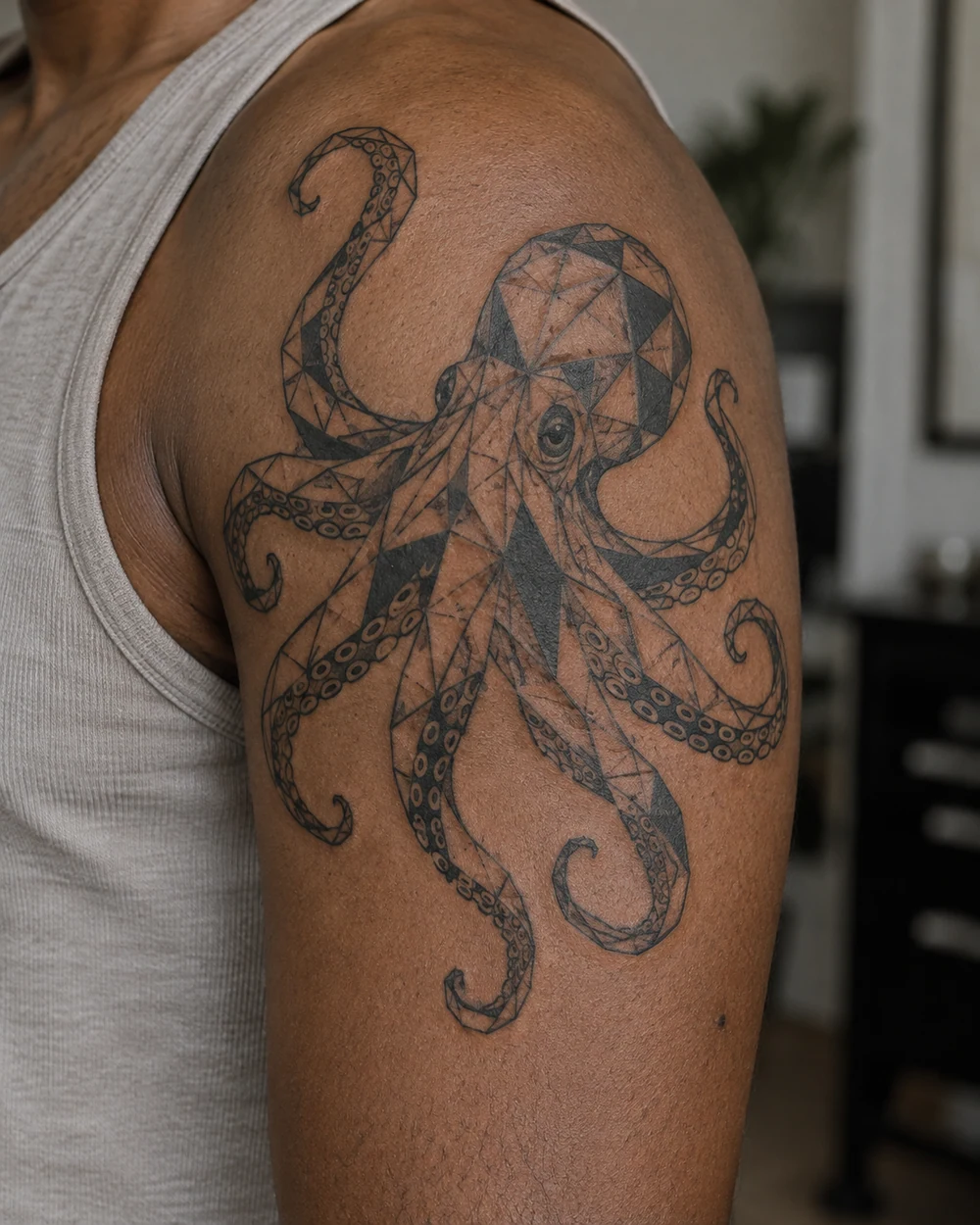 Geometric octopus tattoo with triangular facets on a shoulder and upper arm