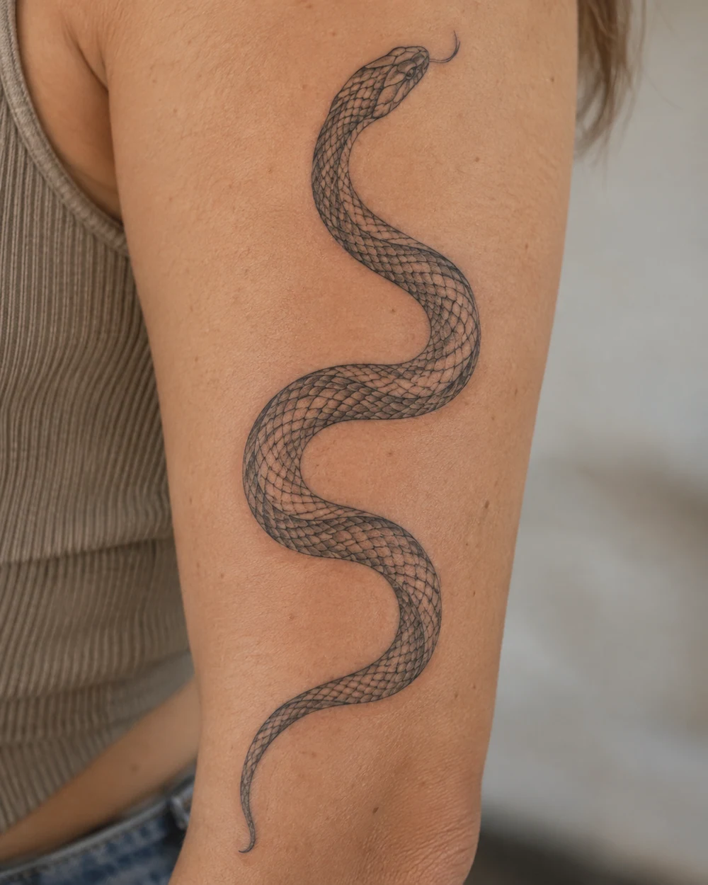Black snake tattoo in an open S-curve on a forearm